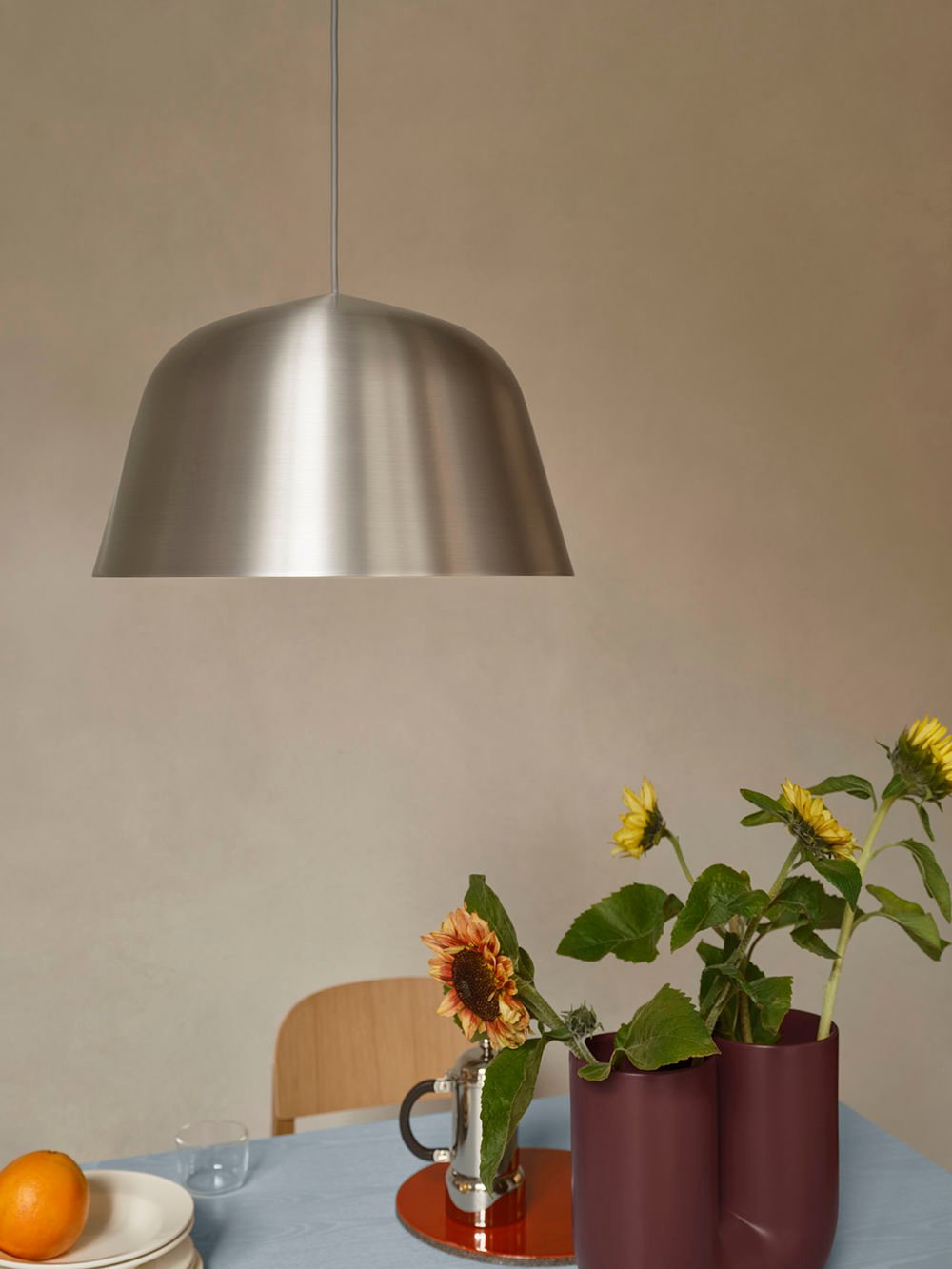 /cdn-cgi/image/width=1500,quality=85,format=auto/globalassets/content-media/images/stories/timelessly-contemporary-ambit-lamp-series/ambit-pendant-brushed-steel-40-kink-vase-deep-red-re-norm-table-light-blue-workshop-chair-oak-low-res.jpg