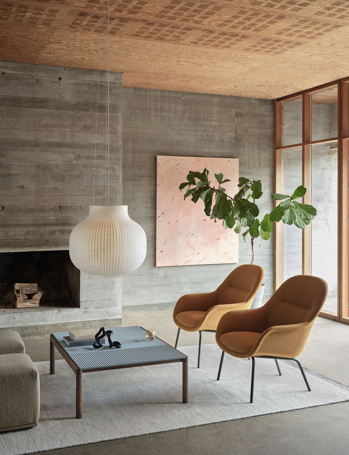 A contemporary Muuto setup featuring a Fiber lounge armchair tube base with Grain 62016 upholstery. The scene includes a Strand pendant light, a Ply rug in off-white made from recycled polyester, and a Couple coffee table. The combination of these elements creates a modern, stylish, and cohesive living space.
