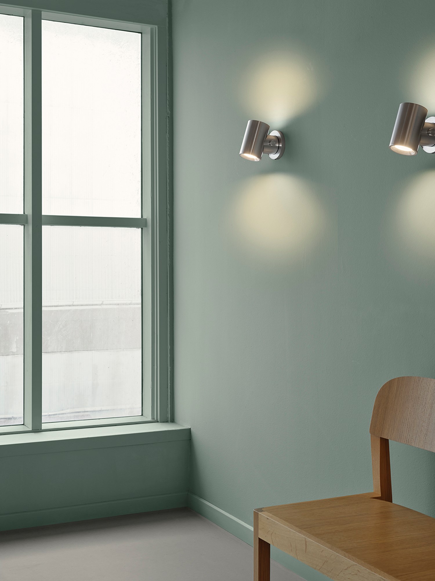 Two Beam Wall Lampa in polished aluminium casting a warm, comfortable light in a soft green room. Two Beam Wall Lampa in polished aluminium casting a warm, comfortable light in a soft green room.