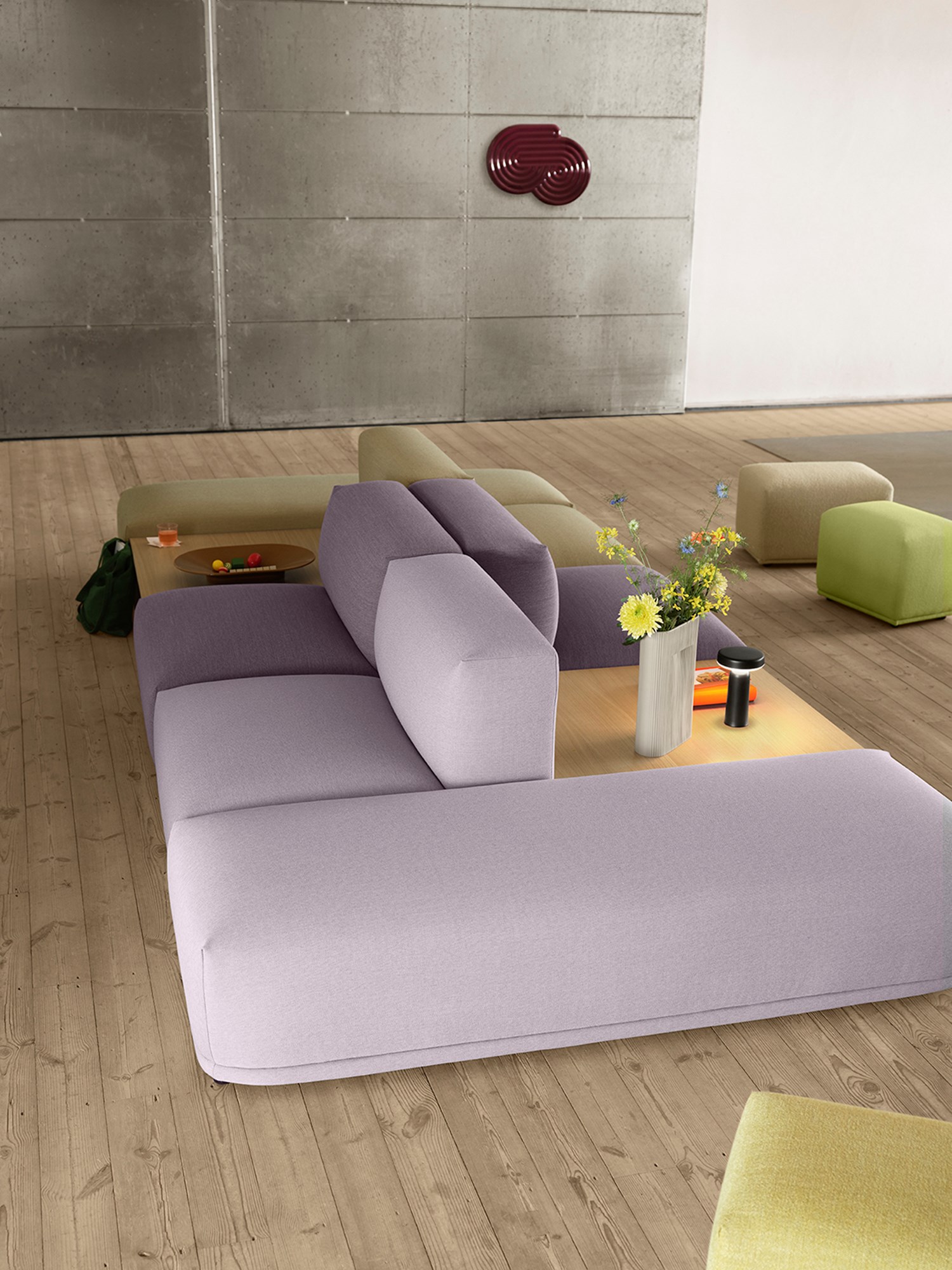 Connect Sofa in a light purple color in a spacious, minimalistic room with white and grey walls, accented by three glass pendant lights hanging above. Connect Sofa in a light purple color in a spacious, minimalistic room with white and grey walls, accented by three glass pendant lights hanging above.