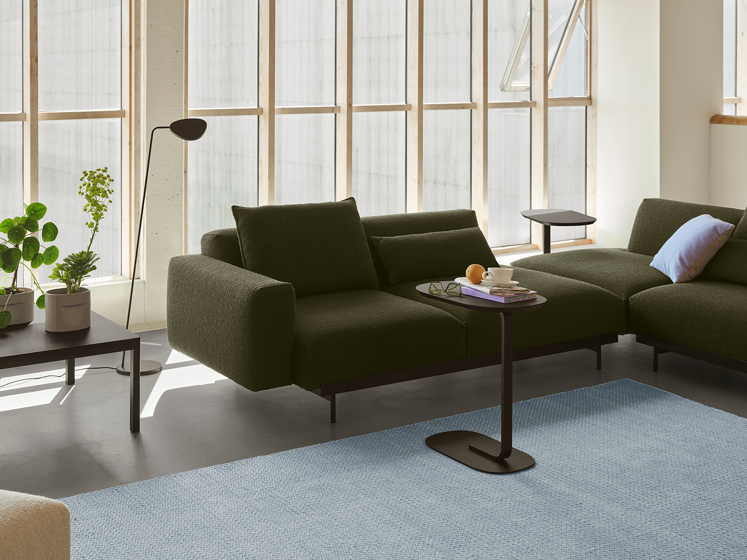 In Situ Sofa in a dark color positioned between a modern floor lamp and a simple sofa table, creating a clean Nordic look.