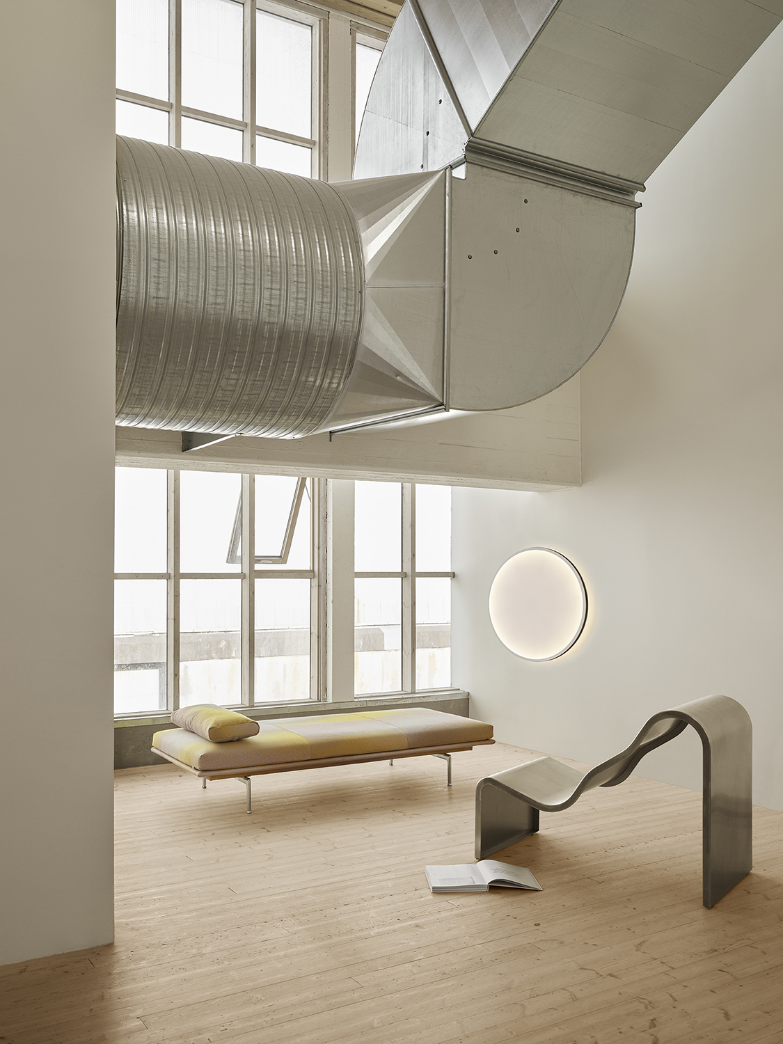 Dream View sofa placed in a simple, minimalistic room with a round wall lamp casting a soft halo of light.