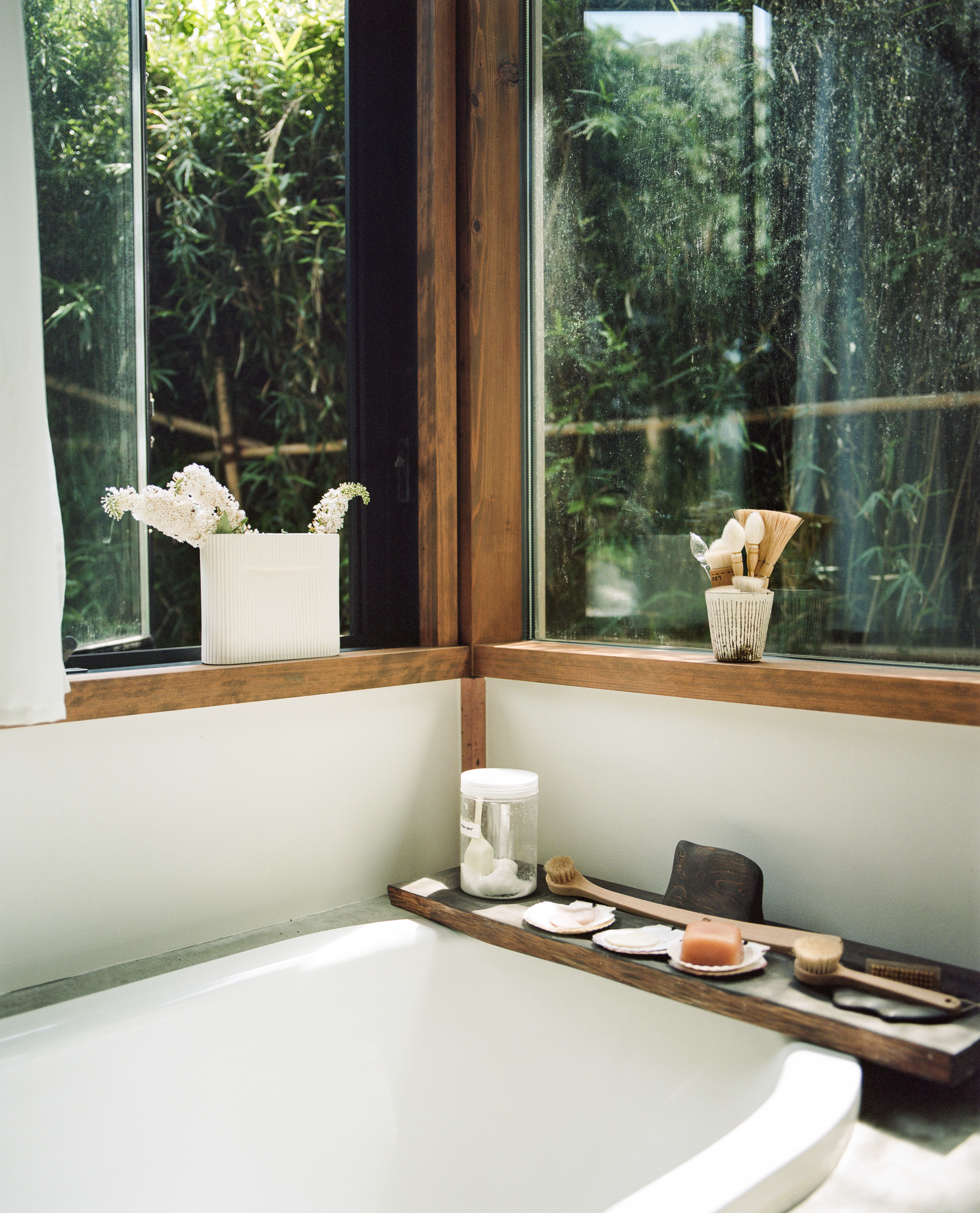 Serene bathroom with a bathtub overlooking a lush garden through a full-length window.