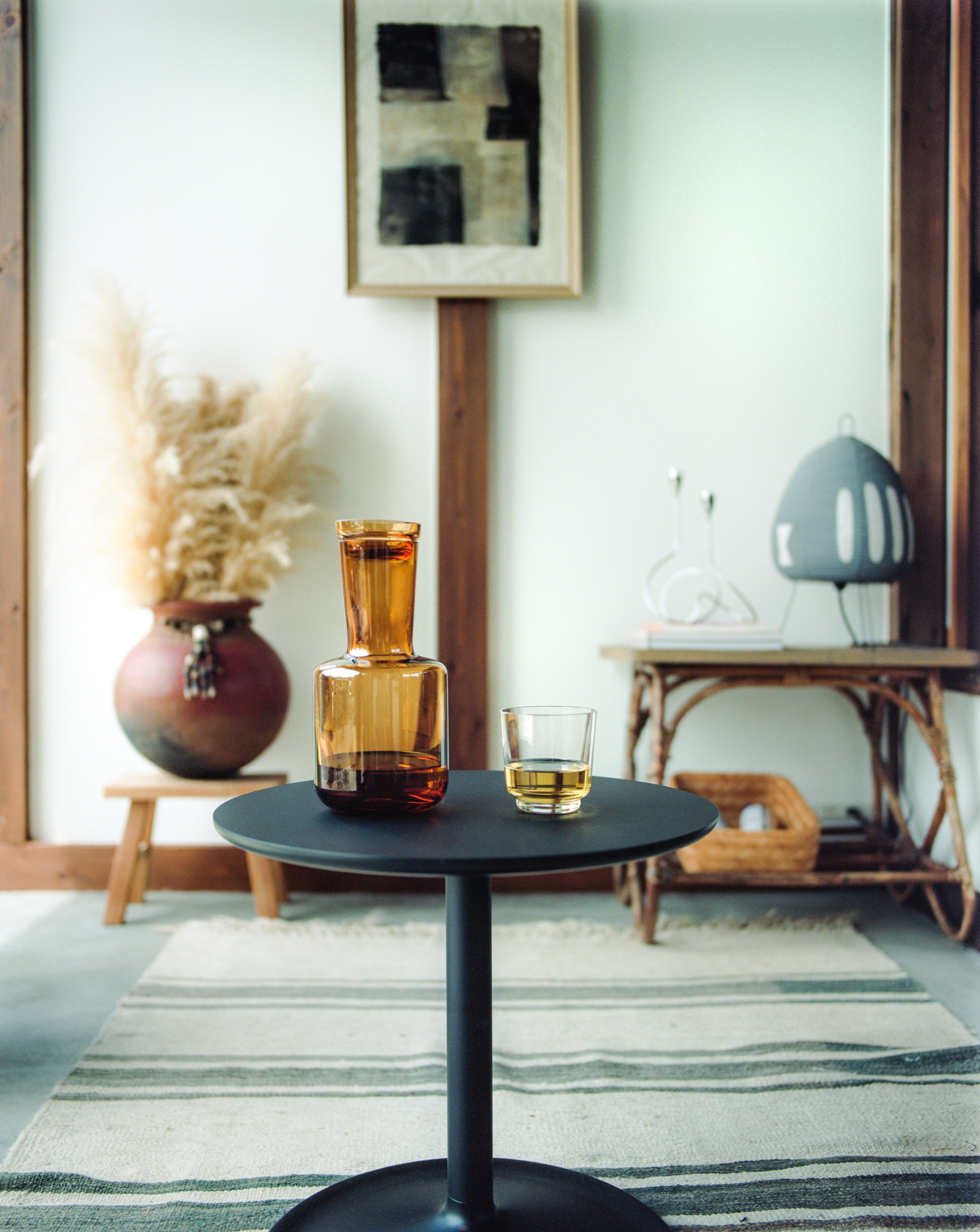 Modern side table with the Raise carafe and glass in a minimalist room.