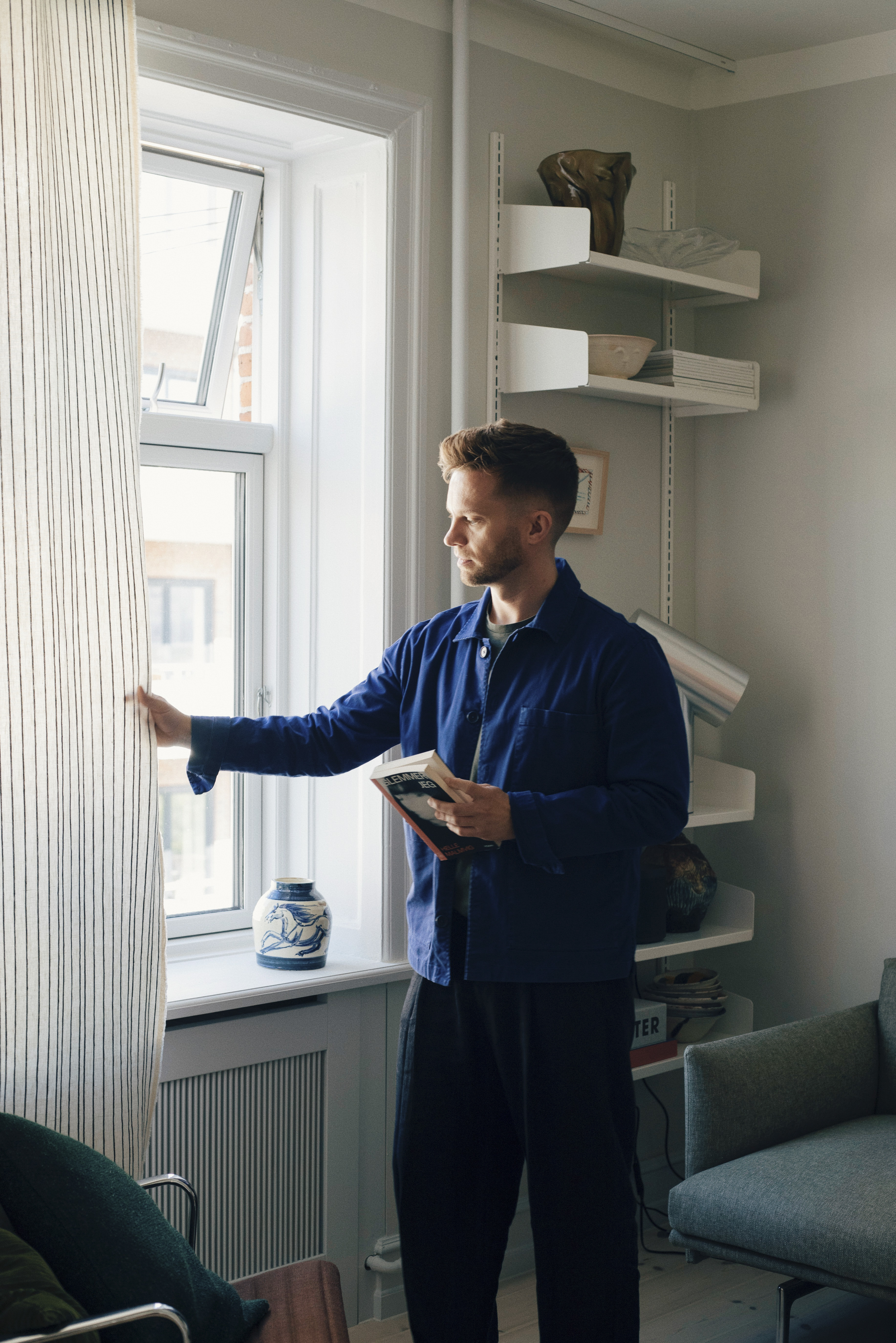Designer Michael Schneider in his home, in a bright and minimal interior styled with warm materials and designs.