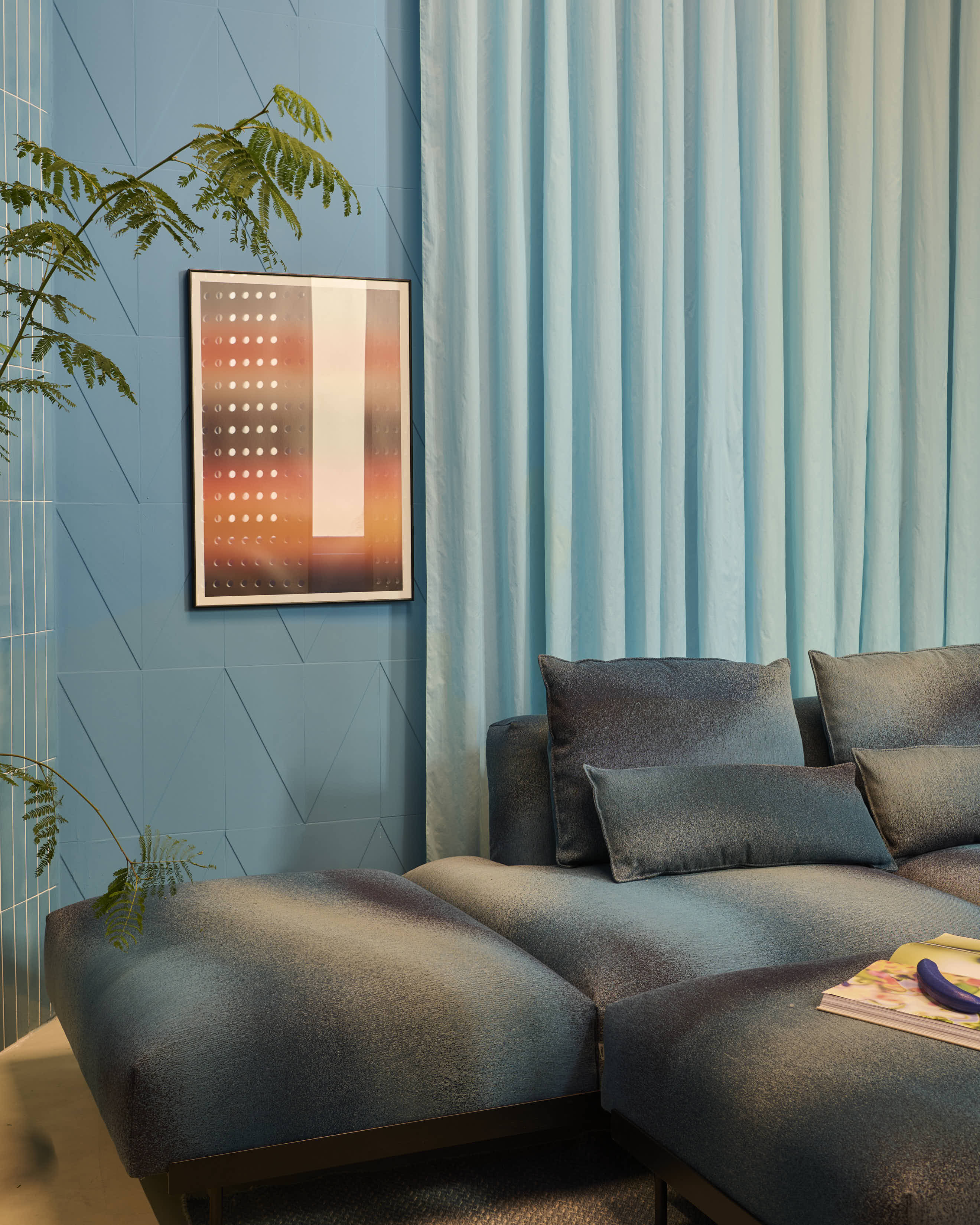 A light blue room with matching curtains. A large dark blue couch is placed along the wall, creating a cozy and comfortable lounge area.
