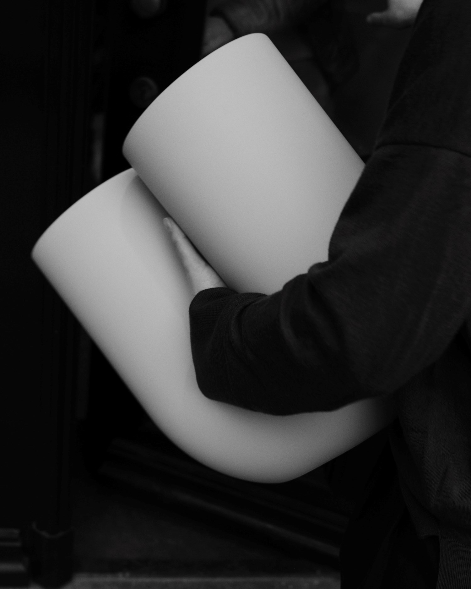 In a black-and-white close-up, Rachel holds a Kink Vase close to their torso.
In a black-and-white close-up, Rachel holds a Kink Vase close to their torso.