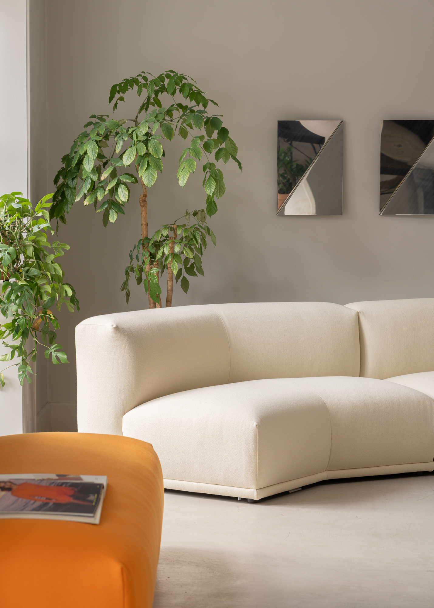 A white Connect sofa placed in a minimalist modern room, accented by artistic mirrors on the wall.