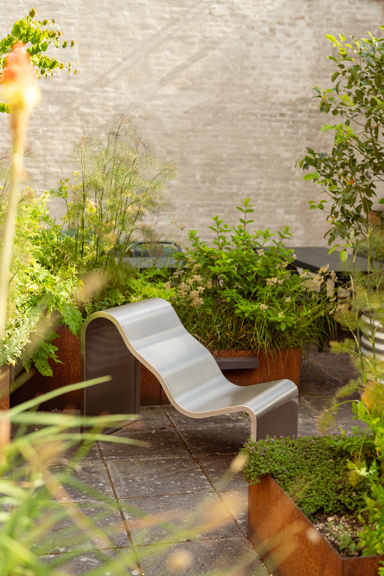 Dream View Chairs placed in a sunny courtyard surrounded by green plants.