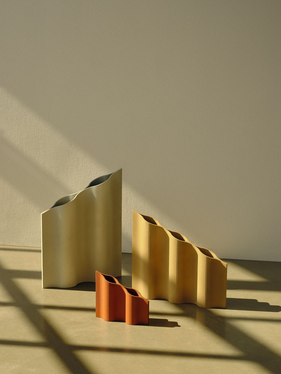 The same three “Waves” vases—cream, ochre, and terracotta—are displayed empty, emphasizing their clean, contoured profiles and material texture. 